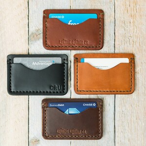 Puede incluir: Cuatro porta tarjetas de cuero en diferentes colores y marcas. Los porta tarjetas son marr&oacute;n, negro, tostado y marr&oacute;n oscuro. Las marcas son Chase, AAdvantage, CRU y Lifetime Leather Co.