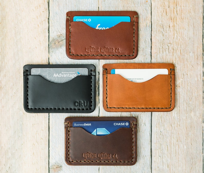 Puede incluir: Cuatro porta tarjetas de cuero en diferentes colores y marcas. Los porta tarjetas son marr&oacute;n, negro, tostado y marr&oacute;n oscuro. Las marcas son Chase, AAdvantage, CRU y Lifetime Leather Co.