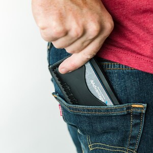 Puede incluir: Una cartera de cuero negra con una tarjeta azul y blanca en su interior. La cartera est&aacute; guardada en un bolsillo trasero de unos vaqueros azules.