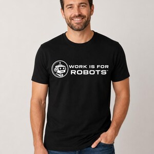 Puede incluir: Camiseta negra con el texto blanco "WORK IS FOR ROBOTS" y un logotipo de cabeza de robot. La camiseta es de cuello redondo.