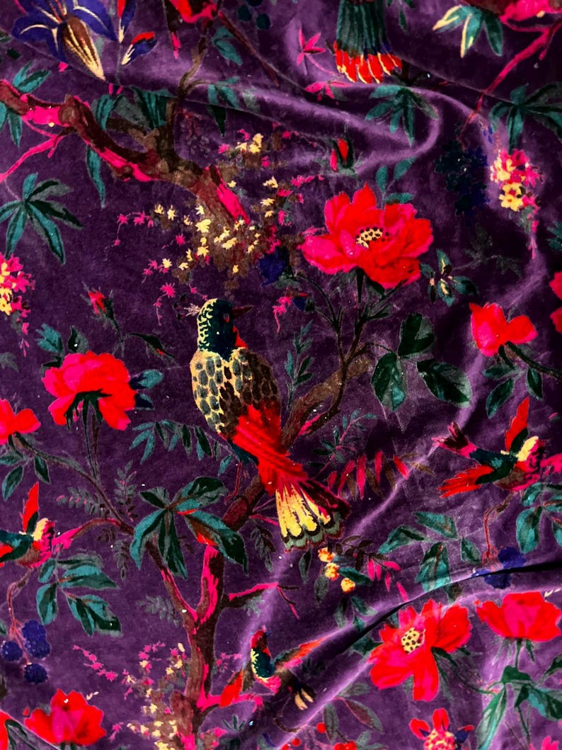 May include: A deep purple velvet fabric featuring a vibrant botanical print. The pattern displays colorful birds perched on tree branches surrounded by large red flowers, green leaves, and small yellow blossoms scattered across the dark surface.
