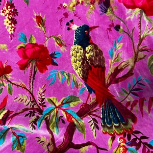 Puede incluir: Una tela de color magenta vibrante con un patr&oacute;n repetitivo de aves coloridas con cabezas azul oscuro, pechos amarillos y colas rojas posadas en ramas. El dise&ntilde;o incluye grandes rosas rojas, hojas verdes y peque&ntilde;os racimos de flores amarillas.