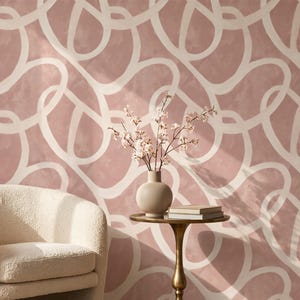 May include: Wallpaper featuring a repeating pattern of thick, off-white, interconnected loops set against a dusty rose background. The design creates a continuous, fluid aesthetic across the surface, providing a soft, muted color palette.