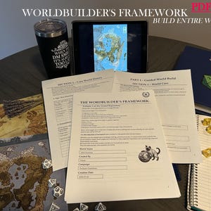 May include: A Worldbuilder's Framework document set featuring printed pages with text and a cat illustration, a tablet displaying a map, a black tumbler with white text, several yellow and white polyhedral dice, and a decorative metal pen.