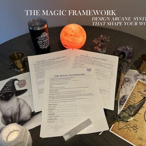 May include: A collection of printed documents titled The Magic Framework, featuring sections on arcane systems, alongside a black tumbler, a glowing orange sphere, brass cups, a cat illustration in a witch hat, crystals, and a metallic quill pen.