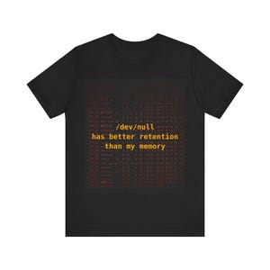 May include: Black t-shirt with a computer code design in red and the text "/dev/null has better retention than my memory" in orange. The shirt is a short-sleeved crew neck.