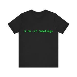 Op de afbeelding: Zwart T-shirt met de tekst "$ rm -rf /meetings" in groen, een opdrachtregelprompt. Het shirt is een crew neck met korte mouwen.
