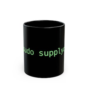 Puede incluir: Una taza de cerámica negra con las palabras "sudo supply" impresas en verde. La taza es cilíndrica y tiene un acabado brillante. El texto está en una fuente sans-serif.