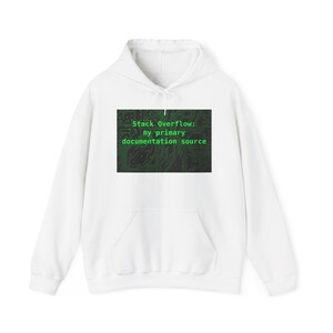 May include: A white long-sleeve hooded sweatshirt featuring a rectangular graphic on the chest. The graphic displays a dark green circuit board pattern with the text "Stack Overflow: my primary documentation source" in a bright green font.