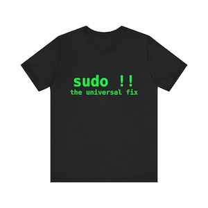 May include: A black short-sleeved t-shirt featuring bright green text printed on the chest. The text reads "sudo !!" on the top line and "the universal fix" on the line below, both in a simple, sans-serif, monospaced computer-style font.
