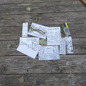 May include: A collection of black and white colouring pages and bookmarks featuring religious themes, including a shepherd with sheep, a cross, and the text Peace on Earth. Four coloured markers in green, orange, blue, and yellow are included in the set.