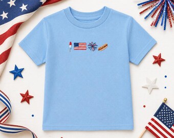 Könnte beinhalten: Ein hellblaues T-Shirt mit kurzen Ärmeln und einer kleinen Stickerei auf der Brust. Das Motiv besteht aus einem rot-weiß-blauen Eis am Stiel, einer amerikanischen Flagge, einem blauen Feuerwerk und einem Hotdog in einer horizontalen Reihe.