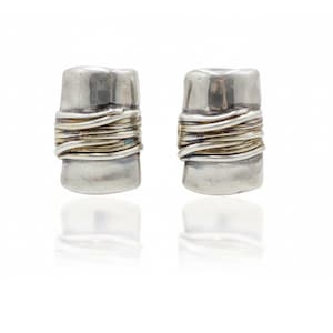 May include: A pair of silver earrings featuring a rectangular, smooth metal base wrapped in multiple thin, coiled silver wires around the centre. The earrings have a polished, reflective finish with a slight tarnish in the crevices.