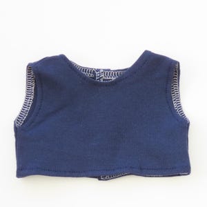 May include: A navy blue sleeveless top with white stitching along the edges. The top has a rounded neckline and a small opening at the back. The fabric appears to be a soft knit material.