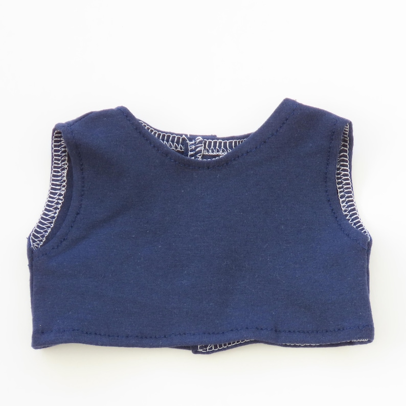 May include: A navy blue sleeveless top with white stitching along the edges. The top has a rounded neckline and a small opening at the back. The fabric appears to be a soft knit material.