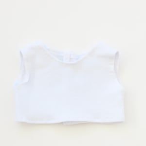 May include: A sleeveless white garment, possibly a top or vest, is centered against a white background. The garment has a rounded neckline and a button closure at the back. The fabric appears to be a soft, lightweight material.
