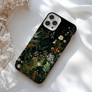 May include: A black smartphone case featuring a detailed botanical print of various green ferns, leaves, and small wildflowers in shades of white, yellow, and orange. The case has a cutout for a triple-lens camera system on the upper left corner.