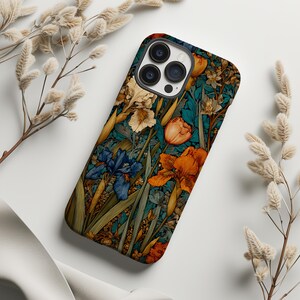 May include: A rectangular smartphone case featuring a dense botanical pattern of orange, blue, and cream-colored iris flowers and green foliage set against a dark teal background. The case has a cutout for a triple-lens camera system on the back.