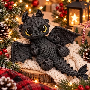 Könnte beinhalten: Ein dunkelgraues, gehäkeltes Drachen-Stofftier mit großen, ausdrucksstarken gelben Augen, spitzen Ohren und breiten Flügeln. Die Figur hat einen strukturierten Körper aus Garn mit kleinen schwarzen Krallen an den Füßen und einem langen Schwanz.