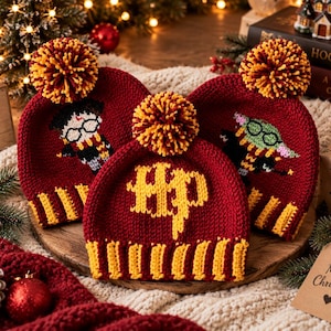 May include: Three maroon and gold knit beanies with pom-poms. One beanie features the yellow letters HP, one displays a character with glasses and a scarf, and one shows a green character with glasses. Each hat has a ribbed brim and a pom-pom on top.