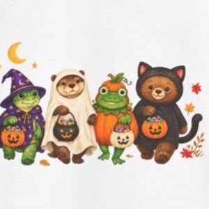 May include: A white t-shirt featuring a colourful illustration of four animals dressed in Halloween costumes: a turtle in a purple wizard hat, an otter in a ghost sheet, a frog in a pumpkin suit, and a bear in a black cat costume, all holding jack-o'-lantern candy buckets.