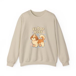 May include: A beige sweatshirt featuring a cartoon Shih Tzu dog with brown and white fur. The dog is standing with a curly tail. The text "FLOOF BOSS" is above the dog in a playful font, with star accents.