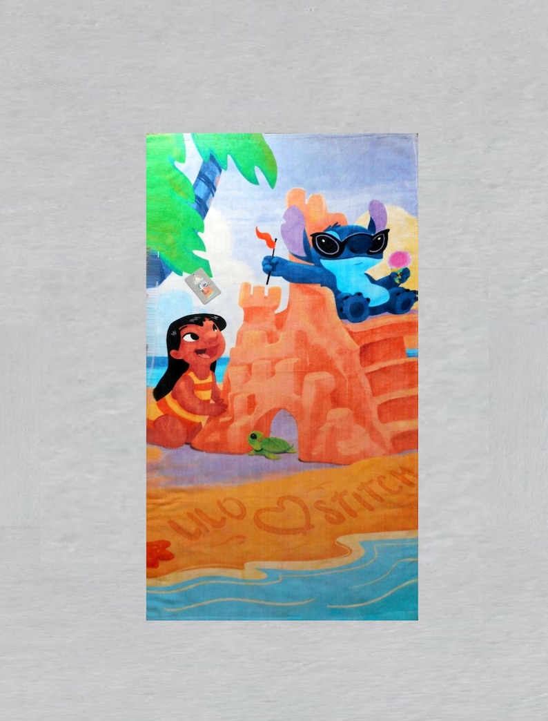 May include: Beach towel featuring a colorful illustration of Lilo and Stitch at the beach. Stitch is wearing sunglasses and holding a flag, while Lilo is building a sandcastle. The towel has the words "Lilo" and "Stitch" on it.