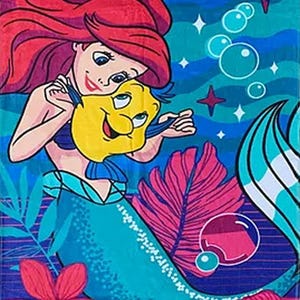 Puede incluir: Una toalla de playa colorida con una ilustraci&oacute;n de dibujos animados de una sirena pelirroja y un pez amarillo. El fondo azul presenta burbujas, estrellas y flores. La sirena sostiene al pez, con detalles en rosa y azul.