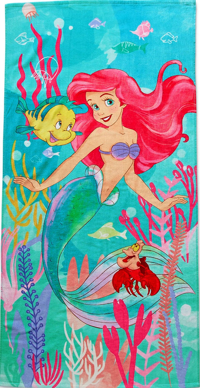 May include: A beach towel featuring a colorful illustration of Ariel, the Little Mermaid, with Flounder and Sebastian. The towel has a turquoise background with coral and other sea life. Ariel has red hair and a purple seashell bra.