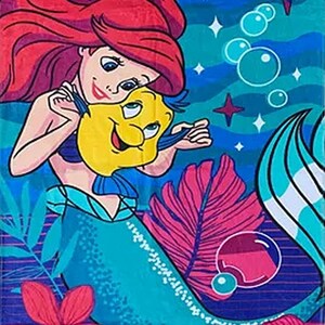 Puede incluir: Una toalla de playa colorida con una sirena de dibujos animados de pelo rojo y un pez amarillo. La toalla tiene un fondo azul con burbujas, estrellas y flores. El dise&ntilde;o es vibrante y alegre, perfecto para ni&ntilde;os.