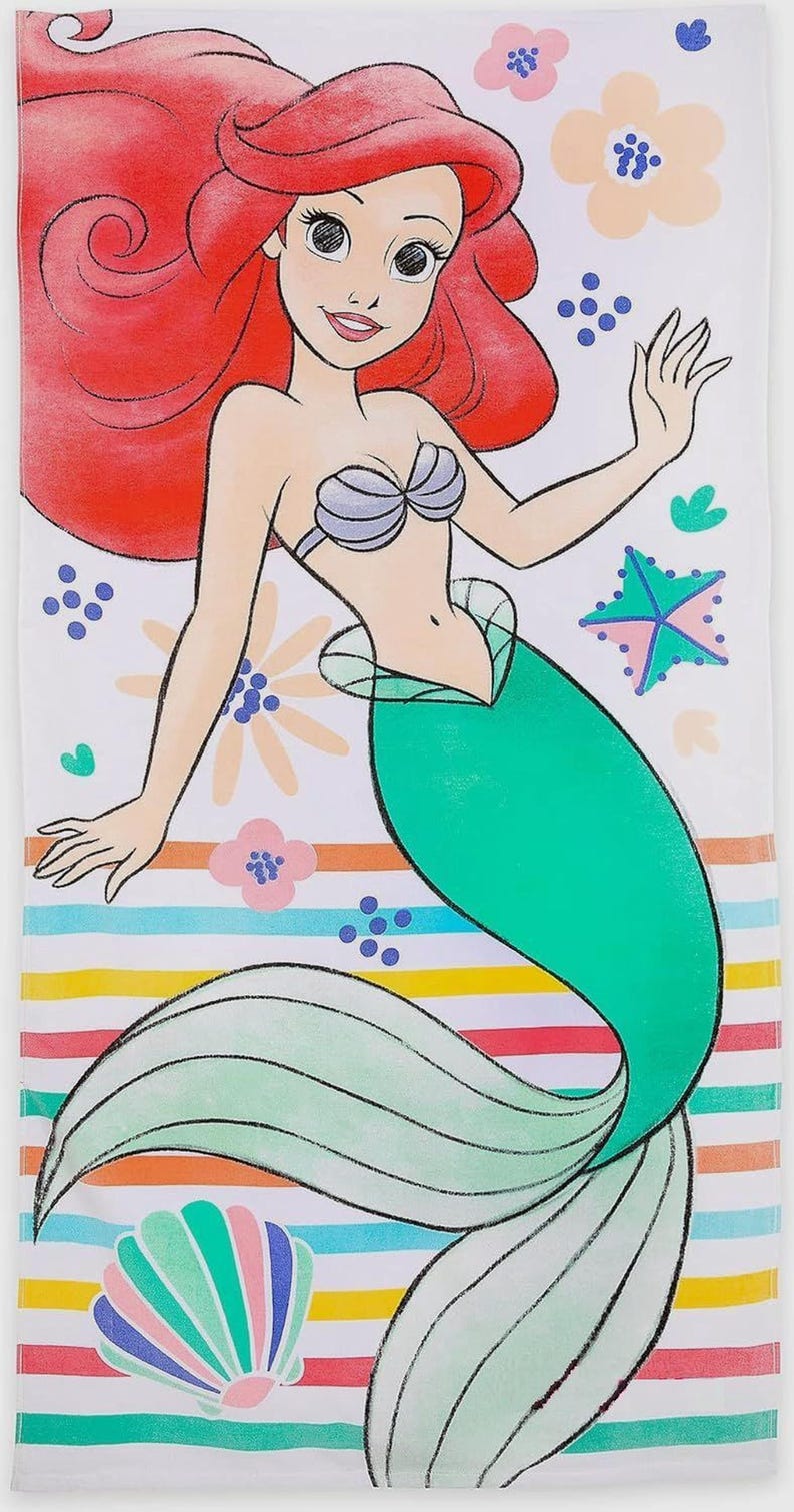 May include: A white beach towel featuring a cartoon illustration of a mermaid with red hair and a green tail. The towel has a striped pattern in various colors, with floral and starfish accents.