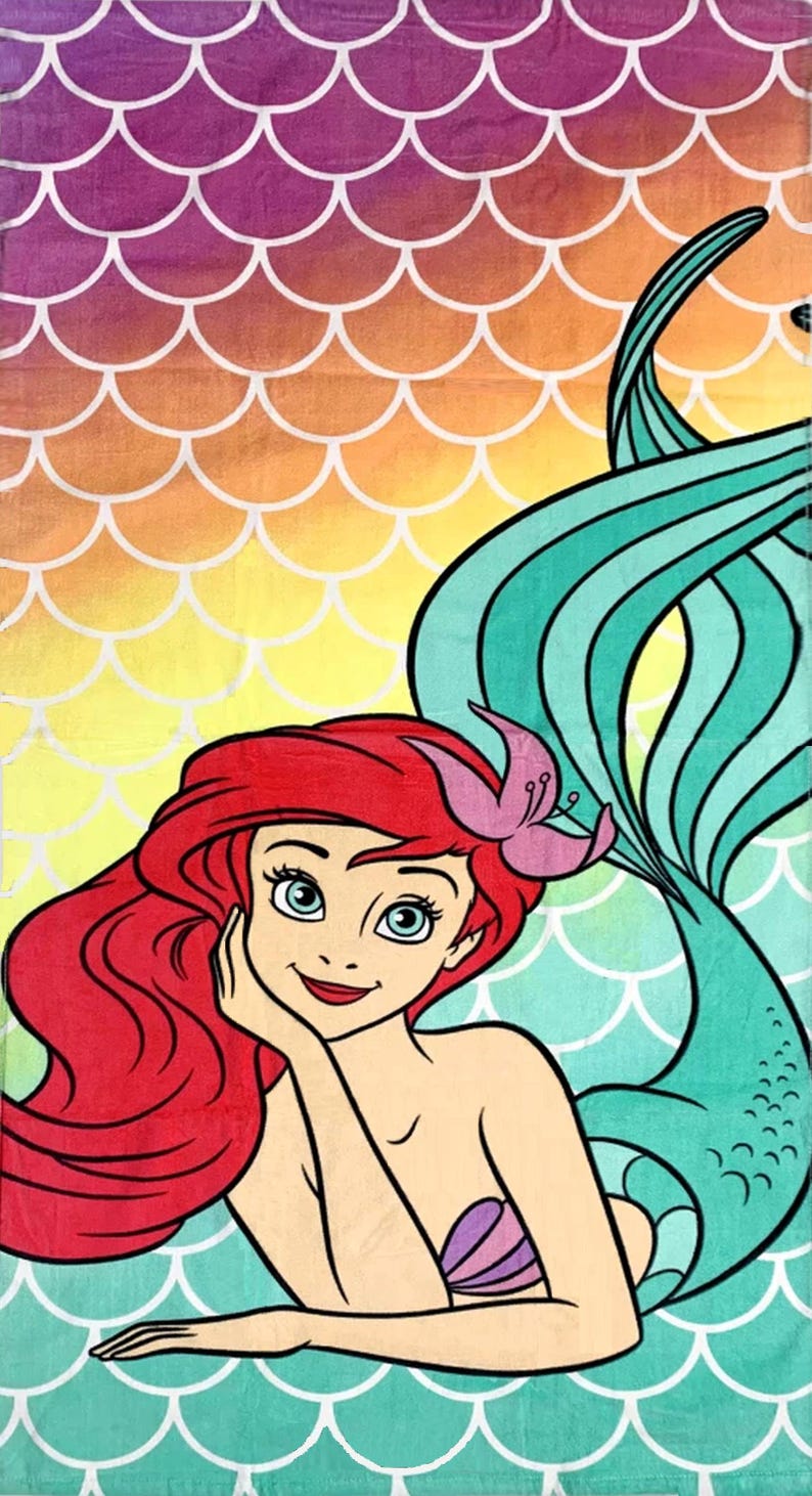 May include: A colorful beach towel featuring a cartoon mermaid with red hair, a pink flower, and a teal tail. The background has a gradient of purple, orange, and yellow with a white scale pattern. The mermaid is smiling and resting her chin on her hand.