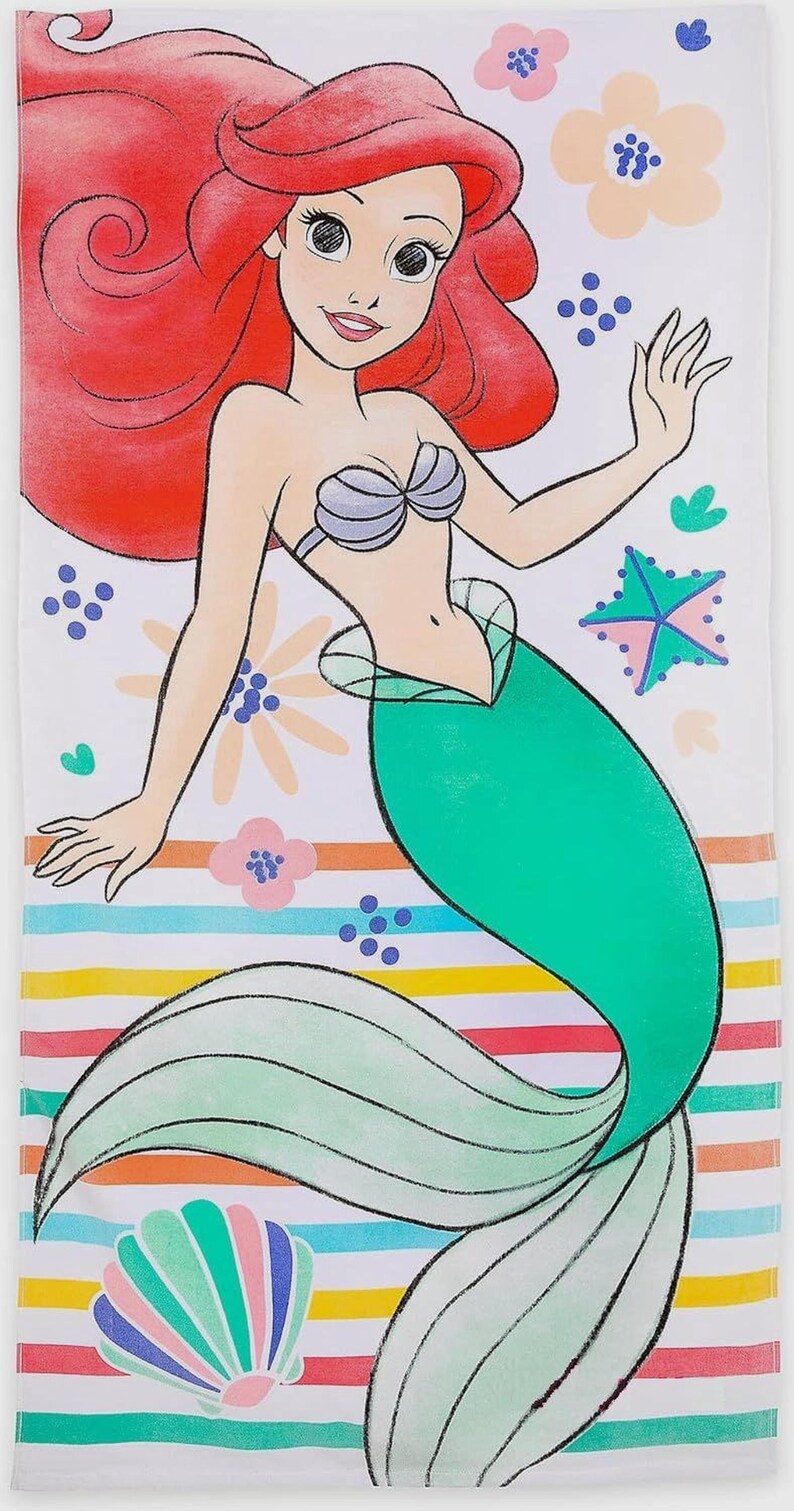 May include: A white beach towel featuring a cartoon illustration of a mermaid with red hair and a green tail. The towel has a striped pattern in various colors, with floral and starfish accents. The mermaid is wearing a seashell bra.