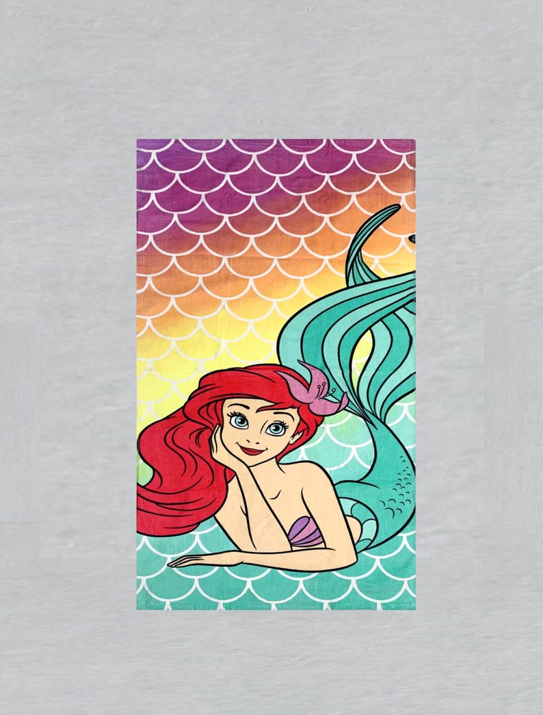 May include: A rectangular beach towel featuring a cartoon illustration of a mermaid with red hair, a purple seashell top, and a turquoise tail. The background has a gradient of colors, including yellow, orange, and purple, with a white scale pattern.