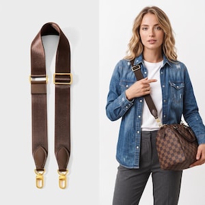 May include: A dark brown adjustable nylon bag strap featuring gold-toned metal hardware, including sliding buckles and swivel lobster clasps at each end, with smooth leather tabs connecting the strap to the metal clips for a secure attachment.