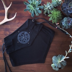 May include: Black cotton wrap skirt with a geometric design and a drawstring closure. The skirt is shown on a wooden surface with succulents.