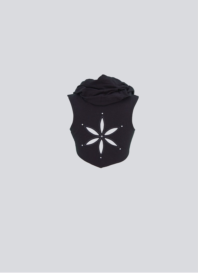 May include: Black sleeveless hooded vest with a white flower cutout on the back.