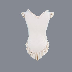 May include: A sleeveless, light pink top with a V-neck and ruffled trim around the neckline, sleeves, and hem.