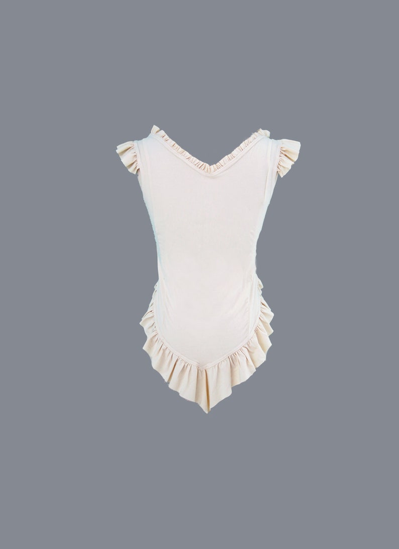 May include: A sleeveless, light pink top with a V-neck and ruffled trim around the neckline, sleeves, and hem.
