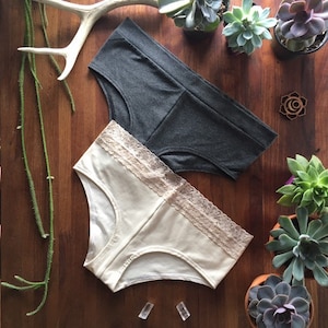 May include: Two pairs of underwear, one gray and one white with lace trim. The white underwear has a lace trim around the top.