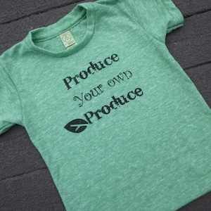 Op de afbeelding: Groen T-shirt met de tekst "Produce your own Produce" en een kleine bladgrafiek.