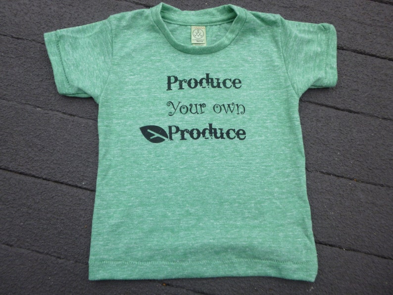 Op de afbeelding: Groen T-shirt met de tekst "Produce your own Produce" en een groene bladafbeelding.
