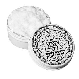 Puede incluir: Una pequeña lata plateada abierta llena de polvo blanco, junto a una tapa con un diseño geométrico en blanco y negro y texto hebreo. La tapa presenta una Estrella de David y un borde decorativo.