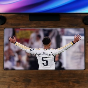 Puede incluir: Una alfombrilla de escritorio rectangular con una impresión de alta resolución de un futbolista visto desde atrás, que lleva una camiseta blanca de manga larga con el nombre BELLINGHAM y el número 5 en negro, con los brazos extendidos en celebración.