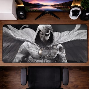 Può includere: Tappetino per scrivania rettangolare in bianco e nero con un'illustrazione di Moon Knight, un personaggio Marvel Comics. L'immagine mostra Moon Knight nel suo costume bianco, completo di cappuccio e mantello. Il tappetino è progettato per un computer ed è lungo circa 80 cm.