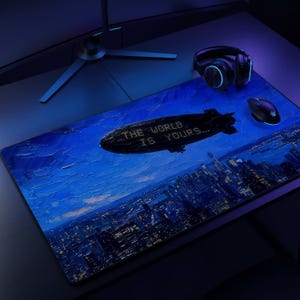 Puede incluir: Una alfombrilla de escritorio rectangular con un paisaje urbano nocturno en azul oscuro y un gran dirigible negro flotando encima. El dirigible tiene el texto THE WORLD IS YOURS impreso en su lateral. Un ratón y auriculares negros están sobre la alfombrilla.