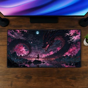 Puede incluir: Una alfombrilla de escritorio rectangular que muestra un dragón oscuro y sinuoso con ojos rojos brillantes y dientes afilados, en un paisaje nocturno con cerezos en flor de color rosa intenso, una luna llena y una pequeña figura sobre una roca.
