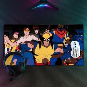 Può includere: Un tappetino da scrivania rettangolare con una colorata illustrazione grafica del team X-Men, incluso Wolverine in primo piano. Un mouse per computer bianco con motivo a nido d'ape si trova sul lato destro e cuffie nere con filo sul lato sinistro.