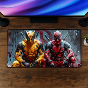 May include: A rectangular desk mat featuring a graphic illustration of two comic book characters, one in a yellow and black suit and the other in a red and black suit, both with swords on their backs, set against a backdrop with red splatters.
