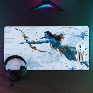 May include: A rectangular desk mat featuring a blue Na'vi character from Avatar aiming a bow and arrow, set against a technical blueprint background with diagrams and text. A black headset and a white perforated gaming mouse rest on the mat.